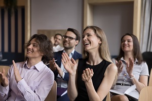 Listeners at an academic conference laughing at a joke and applauding